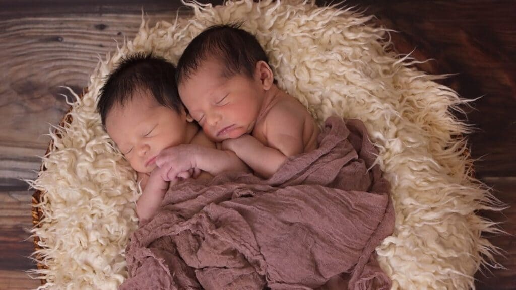 双子の赤ちゃんがラグに同じ姿勢で裸で寝ている