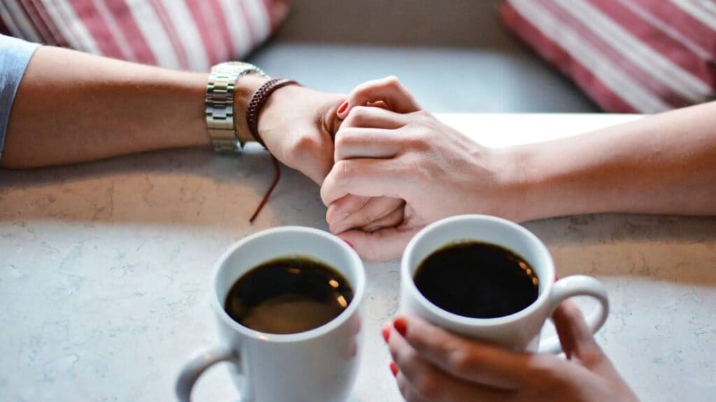 コーヒーを片手に手を握り合っている男女。