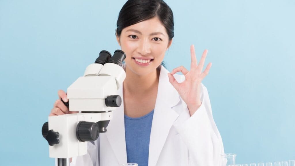 顕微鏡を片手にOKマークを出す女性